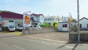 A parking area with several cars, a small building, and a sign with a 'P' symbol. - Maruhei Minshuku (Tateyama)