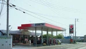 Een tankstation met een rode luifel en het IDEMITSU logo.