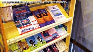 A display of books with various covers, some depicting animals and landscapes, arranged on a shelf. - Maruhei Minshuku (Tateyama)