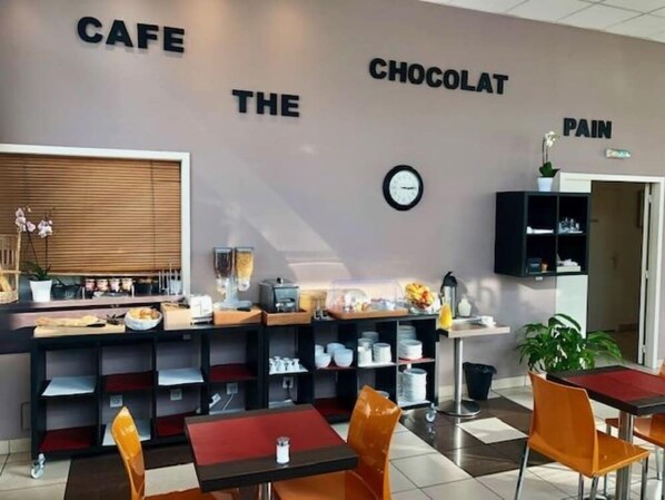Un café con una decoración moderna, que incluye un mostrador con diversos productos, un reloj en la pared y sillas color naranja.
