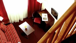 A hotel room with a bed, a desk, a chair, a small table, and a TV. - Adagio Access Grenoble (Grenoble)
