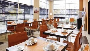 A modern dining area with tables set for breakfast, featuring plates, cups, and cutlery. - Adagio Access Grenoble (Grenoble)