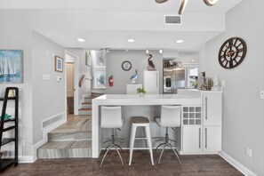 A modern kitchen with a central island, bar stools, and a clock on the wall. - PRIVATE OASIS W/ POOL • SLEEPS 16 • PET FRIENDLY! (Port Aransas)