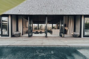Una casa moderna con piscina, ventanas amplias y una zona de estar exterior cubierta.