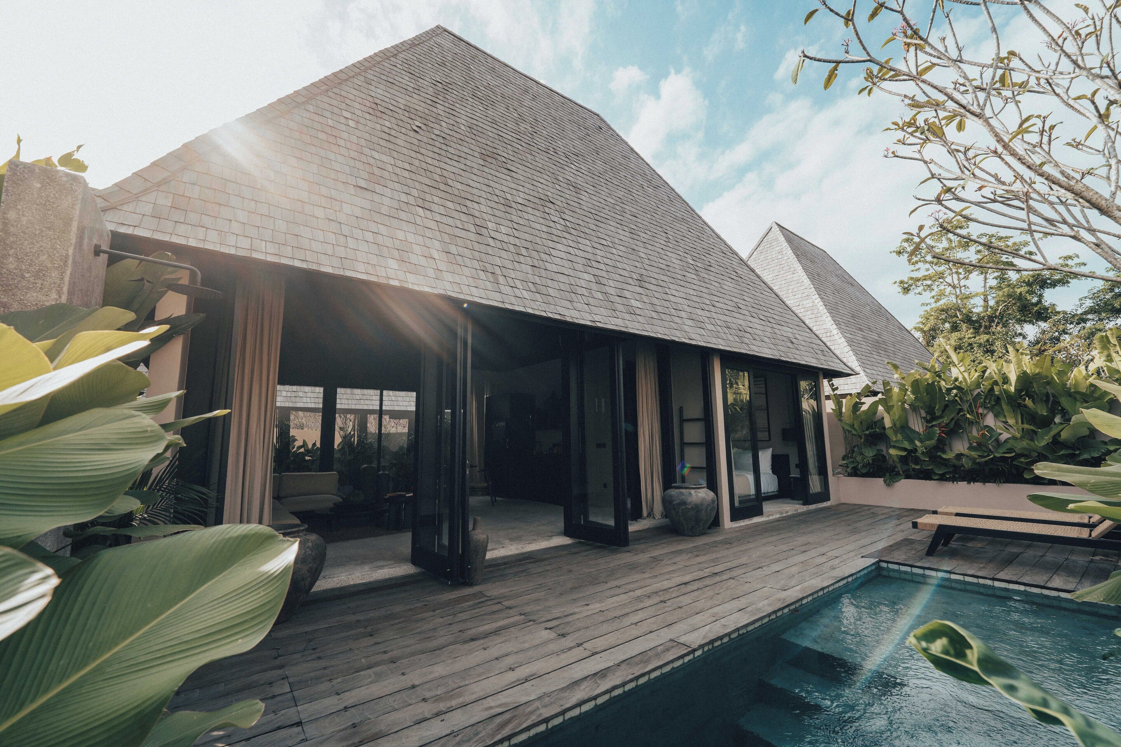 A modern house with a pool, large windows, and a wooden deck.