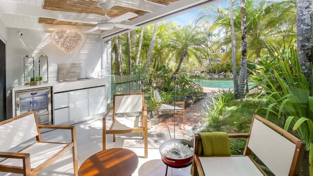 Cozinha moderna com uma grande janela com vista para um jardim tropical e piscina.