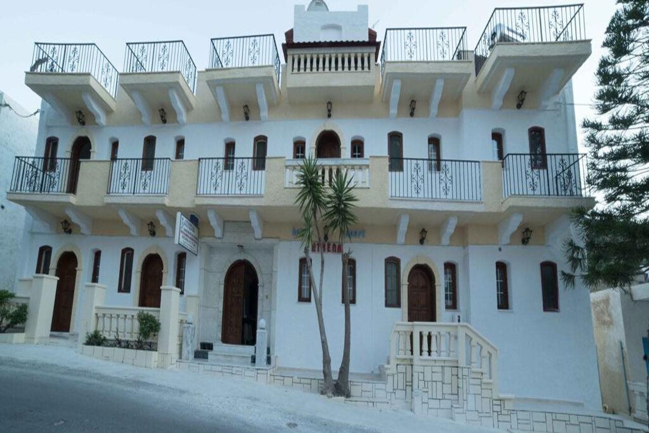 Un edificio de varios pisos con balcones, ventanas arqueadas y una entrada central.