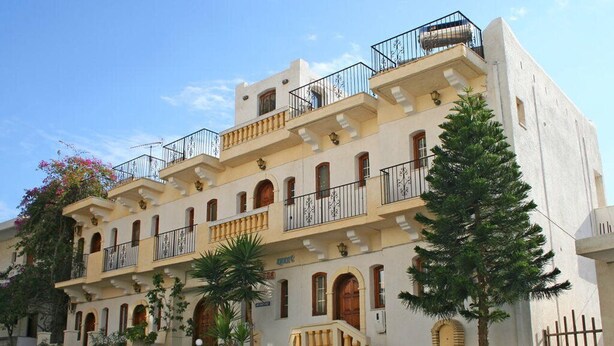 A multi-story building with balconies, arched windows, and a staircase leading to the entrance. - Pallada Apartment (Agios Vasileios)