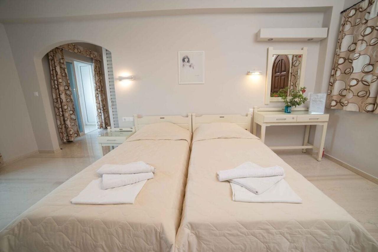 A hotel room with two beds, a desk, a mirror, and a picture on the wall.