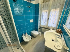 A bathroom with blue tiles, a white sink, a bidet, and a toilet. - Satrico43 - ChiacchioProperty (Rome)