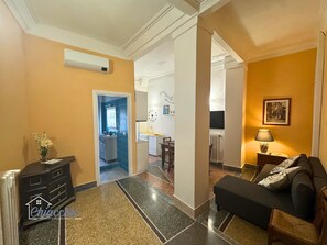 A hotel lobby with a black sofa, a small table with a lamp, a mirror, and a decorative vase. - Satrico43 - ChiacchioProperty (Rome)