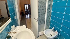 Un baño con un lavabo blanco, una ducha con azulejos azules y una puerta que da a un pasillo.