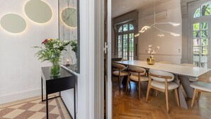 A modern dining area with a long table and chairs, a vase with flowers, and a wall with circular light fixtures. - Ultra Luxurious 3-bedroomHouse with Private Rooftop, Jacuzzi, BBQ area & Office (Buenos Aires)