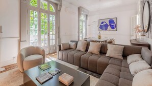 A spacious living room with a large sectional sofa, a round armchair, and a coffee table. There is a dining area in the background with a table and chairs. - Ultra Luxurious 3-bedroomHouse with Private Rooftop, Jacuzzi, BBQ area & Office (Buenos Aires)