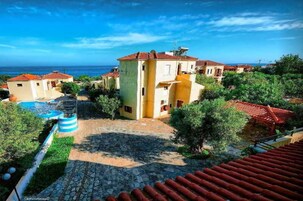 Un barrio residencial costero con edificios de tejas de terracota, un patio empedrado en piedra y una vista despejada al mar.