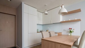 Eine moderne Küche mit weißen Schränken, einem Holztisch und Pendelleuchten.