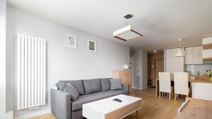 Ein modernes Wohnzimmer mit grauem Sofa, weißem Couchtisch und Holzboden.