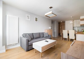 A modern living room with a grey sofa, white coffee table, and wooden flooring. - Rondo ONZ Modern Apartment (Warszawa)