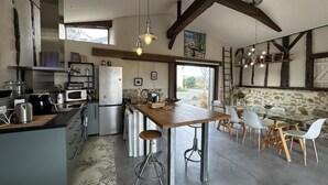 Una cocina amplia con una isla central, electrodomésticos modernos y una zona de comedor con un fondo de pared de piedra.