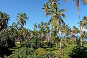 Een tropisch resort met palmbomen, hutten met rieten daken en een helder uitzicht op de oceaan.