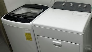 A front-loading washer and dryer unit with a control panel and two faucets on the wall. - Exclusive location, close to the Mall and main attraction. (San Salvador)