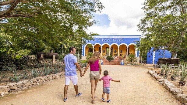 A family walking towards a building with a sign reading "CHOCO-STORY." - Hacienda Uxmal (Santa Elena)