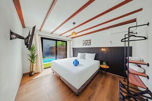 Une chambre moderne avec un grand lit, une porte-fenêtre coulissante donnant sur un balcon, un téléviseur fixé au mur et un porte-serviettes.