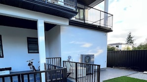 A modern two-story building with a balcony, a concrete driveway, and a green lawn. - 5-Star 1BR Suite | Free Parking & Fast Wi-Fi (Delta)