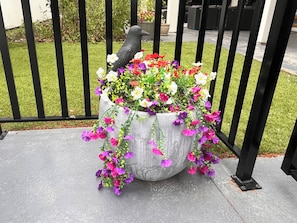A birdhouse with a bird perched on top, surrounded by a planter with various flowers.