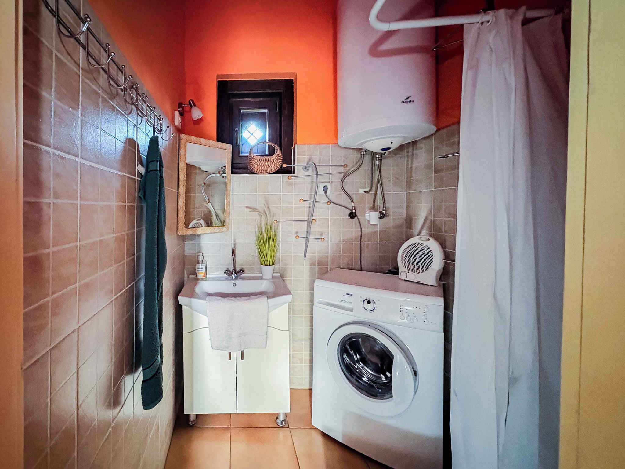 Une petite salle de bain équipée d’un lavabo, d’un miroir, d’un porte-serviettes et d’un lave-linge.