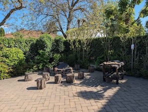 Un espace extérieur aménagé avec un foyer, des tabourets en bois et une pergola.