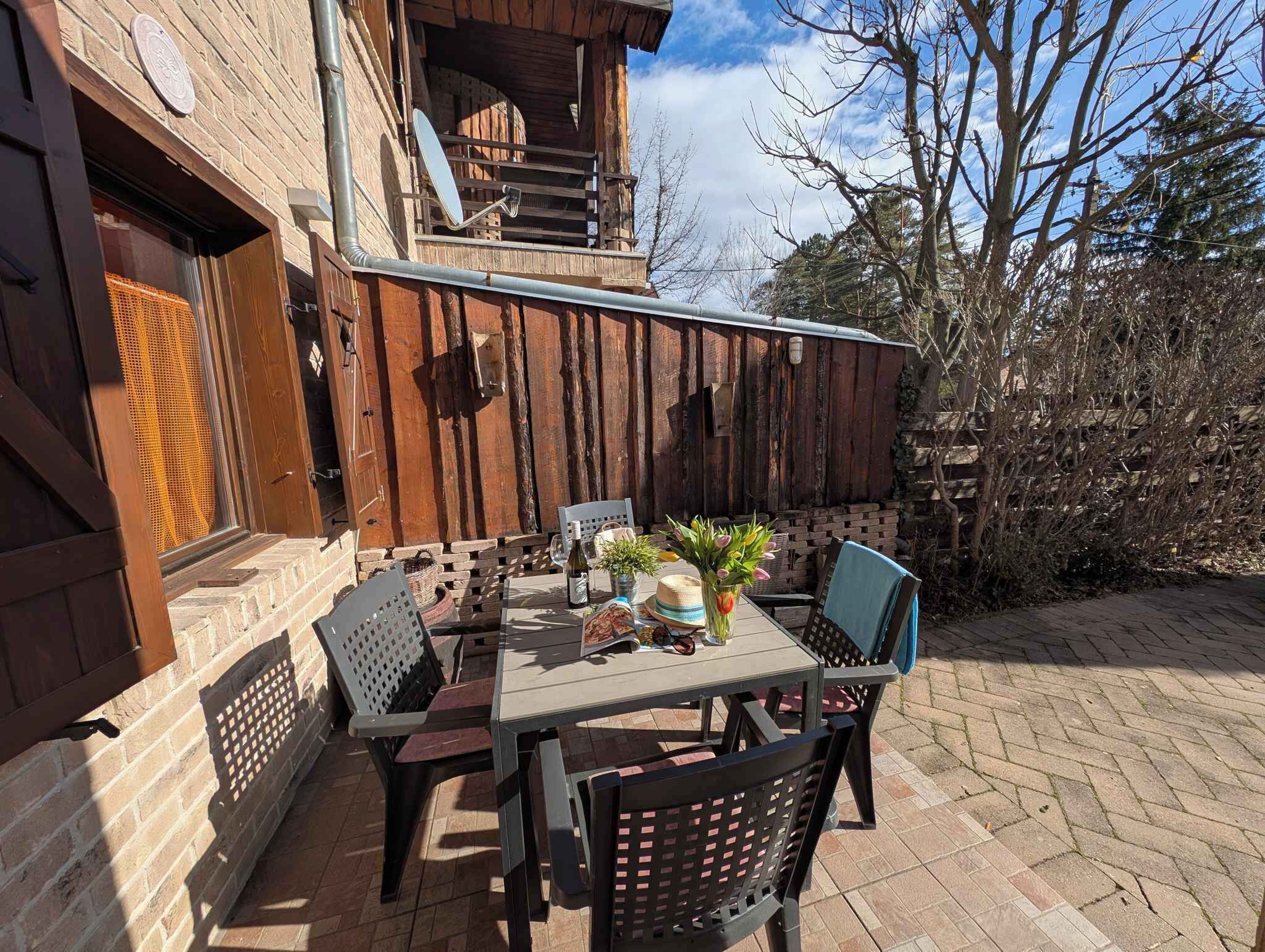 An outdoor patio with a table and chairs, a wooden fence, and a brick wall.