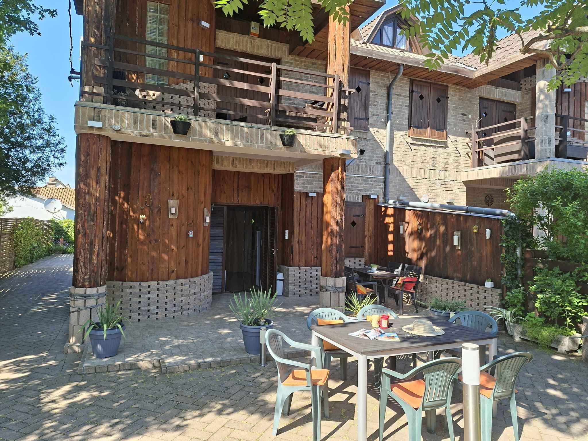 Un edificio de madera con balcón, asientos al aire libre y plantas en macetas.