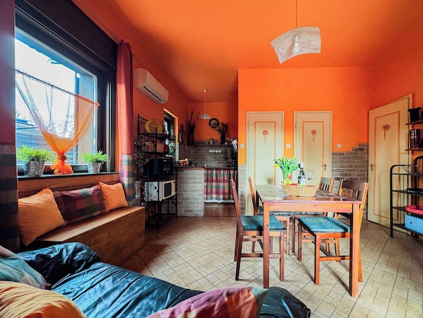 Un salon confortable avec un canapé, une table à manger et des chaises, ainsi qu’un coin cuisine équipé d’un réfrigérateur et d’un four à micro-ondes.