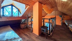 Ein gemütliches Schlafzimmer im Dachgeschoss mit schrägen Wänden, einem Oberlicht und einer Hängematte.