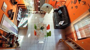 Ein großzügiger Wohnbereich mit einer schwarzen Ledersofa, einem Couchtisch mit floralem Muster und einer Treppe, die zu einer oberen Etage führt.