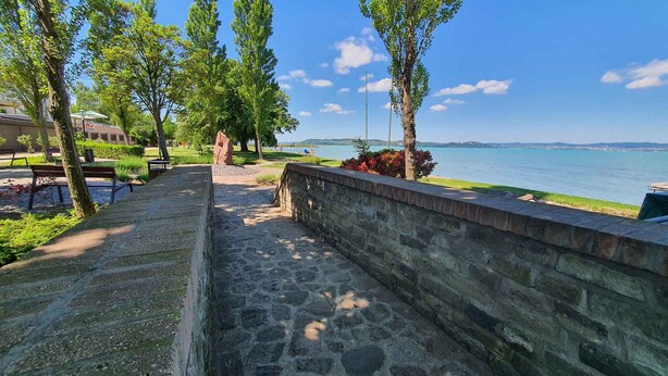 Ein Steinweg führt zum Ufer, wo Bänke und Meerblick warten.