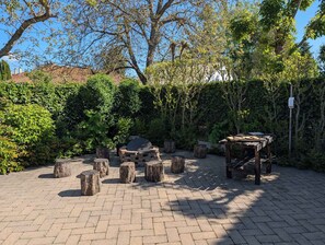 An outdoor seating area with a fire pit, wooden stools, and a pergola.