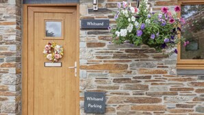 A stone building with a wooden door and a sign indicating 'Whitsand Parking'. - An Skyber in Cornwall (Saltash)