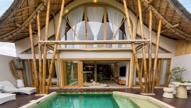 A resort with a large pool, a covered outdoor area, and a distinctive bamboo roof structure. - Sunset Bamboo by Pertama Stay (Kerobokan)