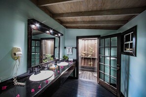 Une salle de bain avec deux lavabos, un grand miroir et un plafond en bois.