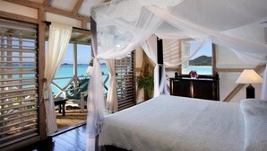 Ein Schlafzimmer mit Himmelbett, Meerblick und einem Balkon mit einem Stuhl.