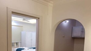 A narrow hallway with a bed and a wardrobe in the background. - Lillywoods Highland Beach Resort (Candolim)