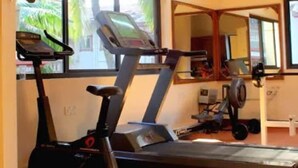 A gym with treadmills and an elliptical machine. - Lillywoods Highland Beach Resort (Candolim)