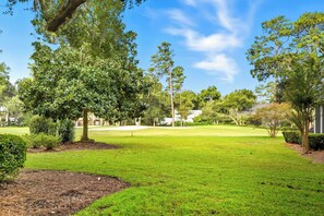 A well-maintained grassy area with trees and a clear sky.