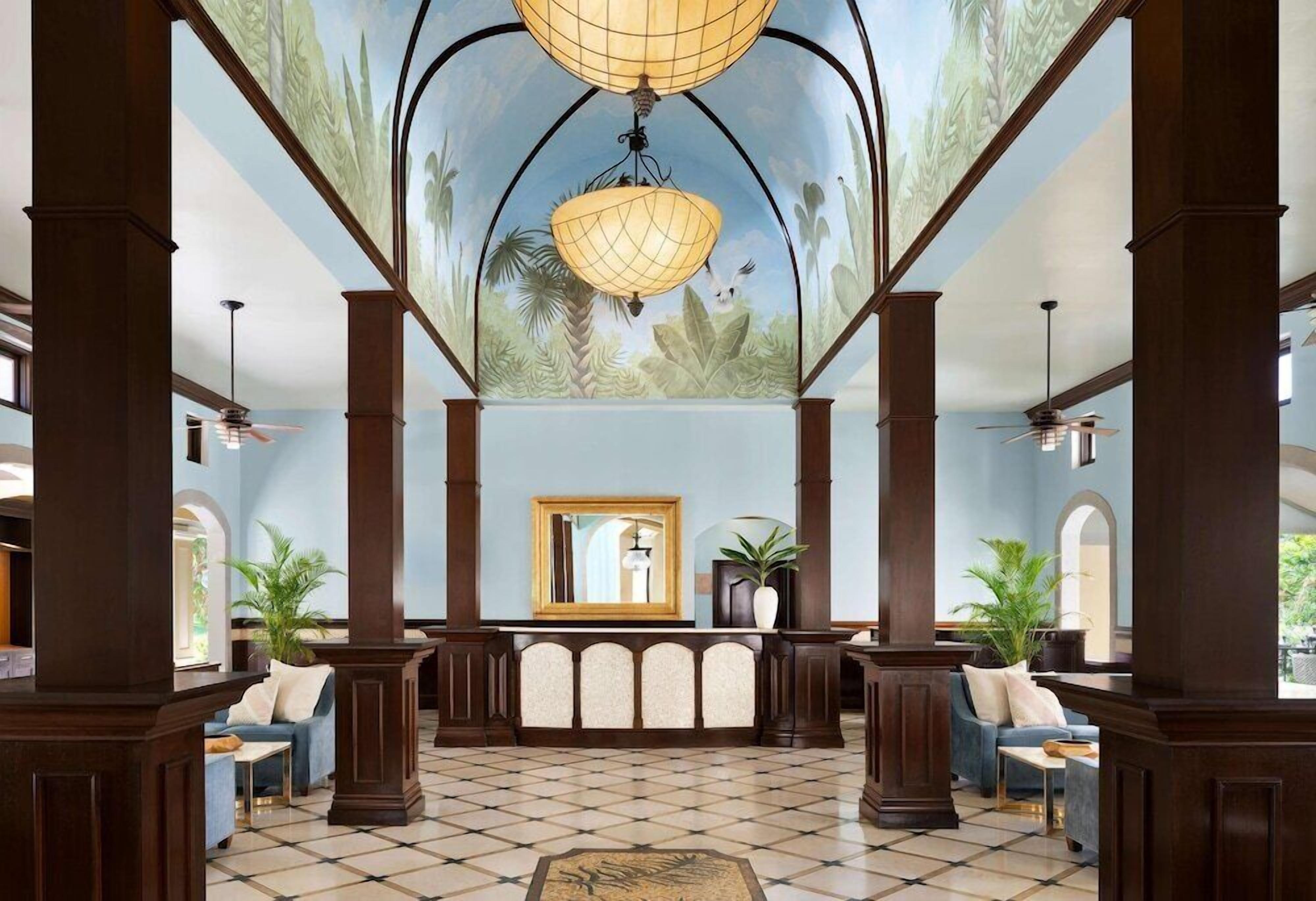 A lobby with a checkered floor, a large mirror, and a ceiling mural.