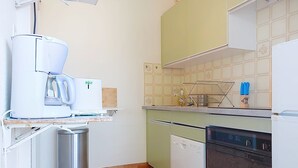 Una cocina compacta con cafetera, basurero, lavavajillas y microondas.