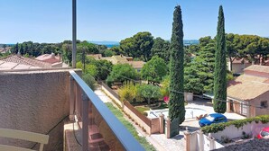 Zona residencial con vista despejada a un patio, altos cipreses y una costa distante.