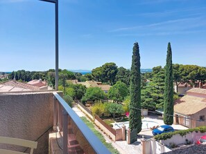 A residential area with a clear view of a courtyard, tall cypress trees, and a distant coastline. - Les Jardins du Soleil by Interhome (Six Fours)