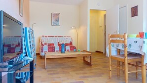 Una sala de estar con sofá, mesa de centro, televisor y un comedor con mesa y sillas.